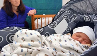 Besorgte Frau neben der Babyschale.